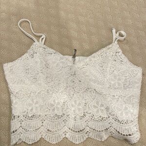 White lace crop top with spaghetti straps and a zipper closure.